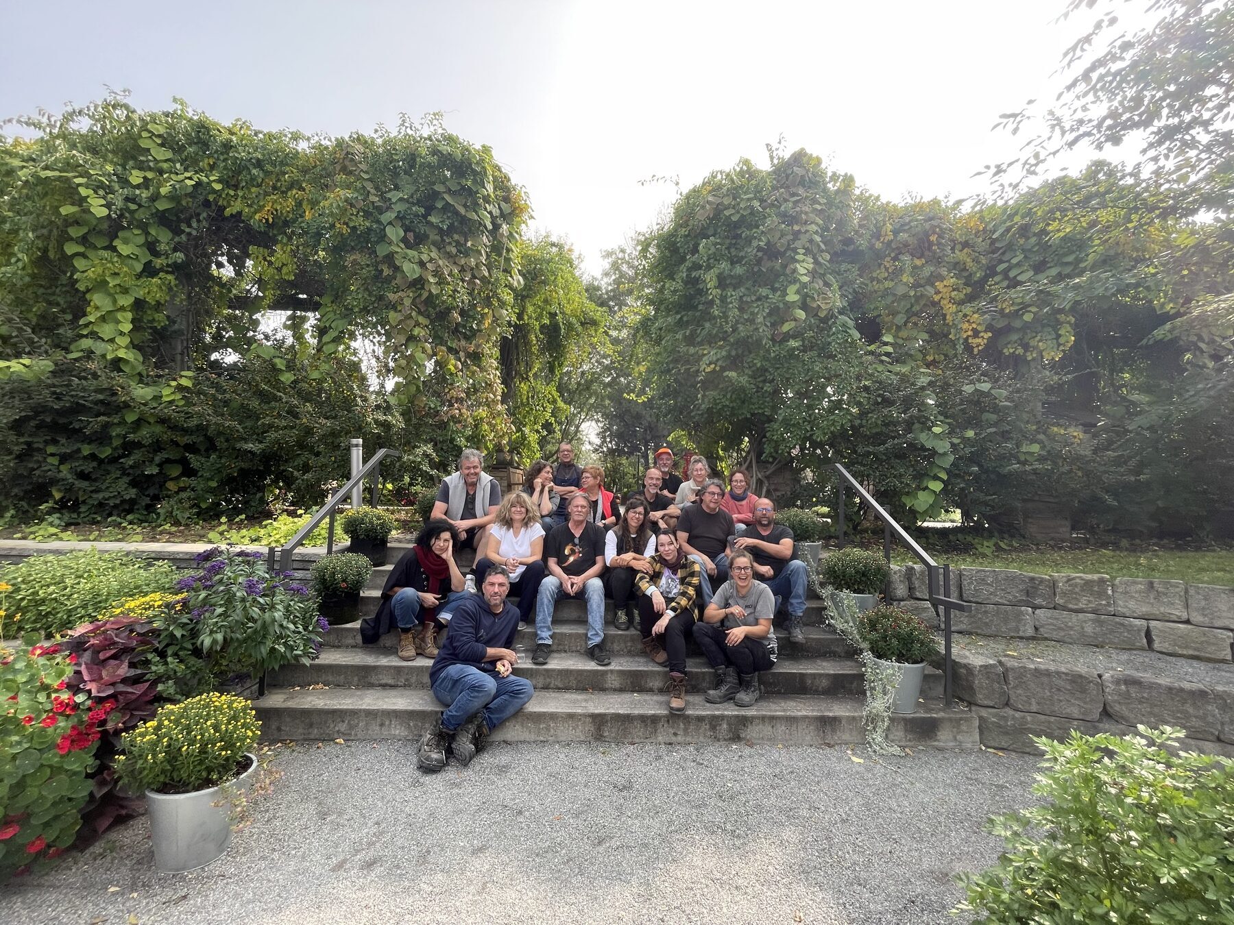 Un groupe d’artistes réuni sur les marches du Jardin Daniel A. Séguin, entouré de végétation.